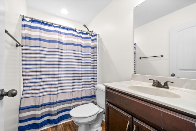 bathroom with walk in shower, hardwood / wood-style floors, vanity, and toilet