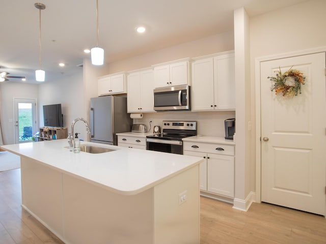 kitchen with stainless steel appliances, hanging light fixtures, a center island with sink, and sink