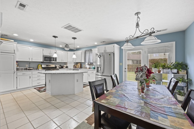 kitchen with a center island, white cabinets, decorative light fixtures, and appliances with stainless steel finishes