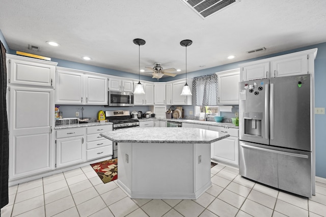 kitchen featuring appliances with stainless steel finishes, ceiling fan, white cabinets, a center island, and light tile patterned flooring