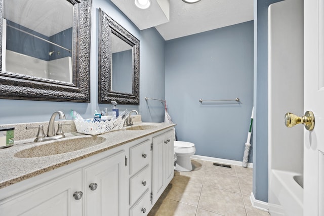 bathroom featuring tile patterned flooring, vanity, a textured ceiling, and toilet