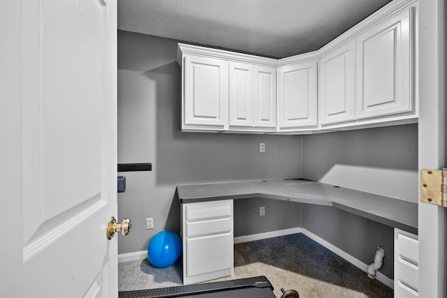 home office with carpet flooring, a textured ceiling, and built in desk