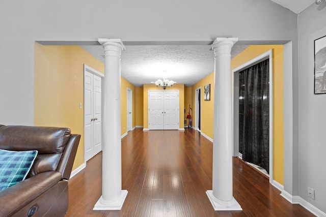 corridor with a textured ceiling, a notable chandelier, and dark wood-type flooring