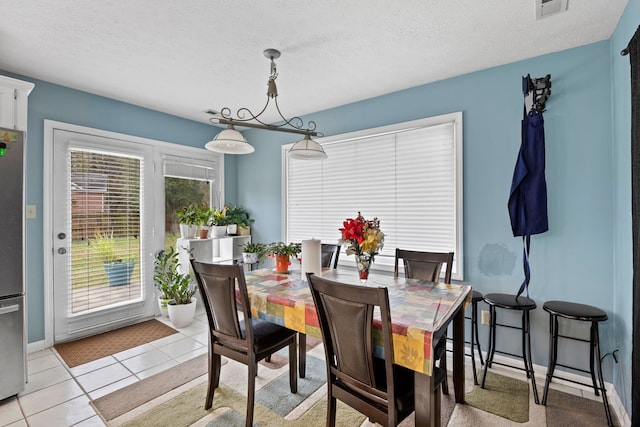 dining area featuring a textured ceiling and light tile patterned flooring