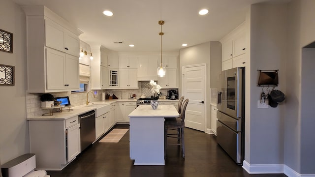 kitchen with a kitchen island, pendant lighting, appliances with stainless steel finishes, and white cabinetry