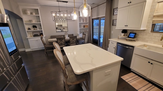 kitchen with a kitchen island, stainless steel dishwasher, decorative light fixtures, and white cabinetry