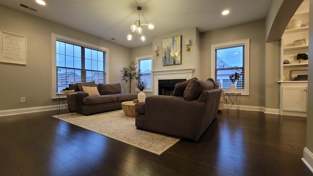 living room with dark hardwood / wood-style floors, a healthy amount of sunlight, and an inviting chandelier