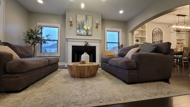 living room featuring a wealth of natural light, a notable chandelier, and hardwood / wood-style flooring