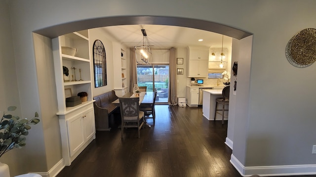 kitchen with pendant lighting, a kitchen breakfast bar, white cabinetry, and dark hardwood / wood-style floors