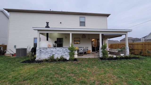 back of property featuring an outdoor living space, central air condition unit, a lawn, and a patio area