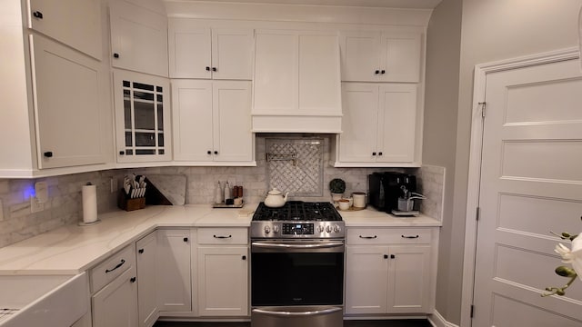 kitchen with white cabinetry, decorative backsplash, and stainless steel gas range