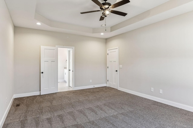 unfurnished room featuring ceiling fan, a raised ceiling, and carpet floors