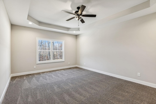 carpeted empty room with a tray ceiling and ceiling fan