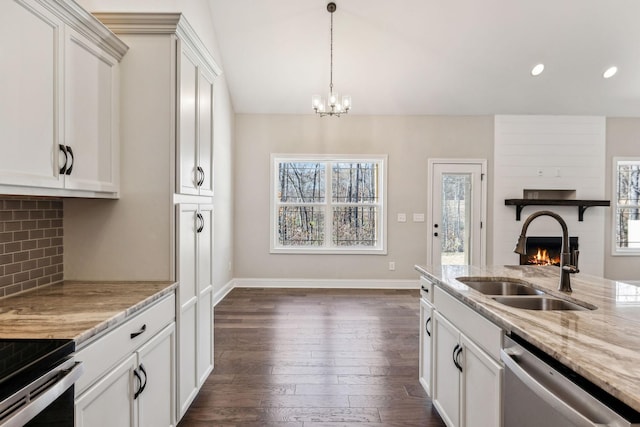 kitchen featuring a large fireplace, white cabinetry, sink, and stainless steel appliances