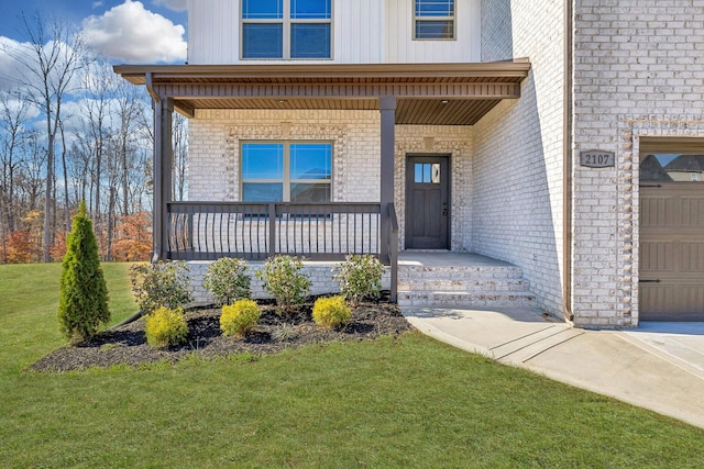 doorway to property featuring a garage, covered porch, and a yard