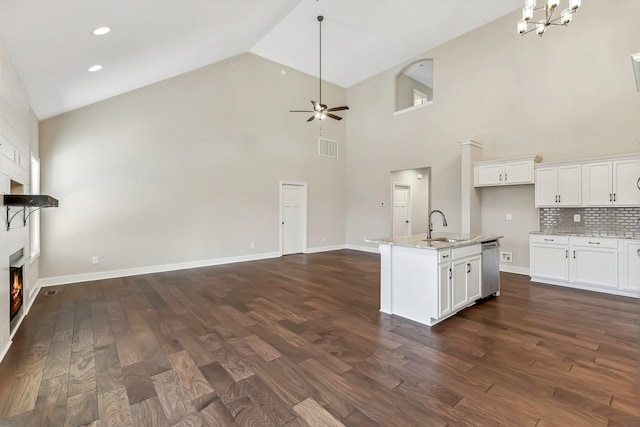 kitchen with white cabinets, ceiling fan with notable chandelier, dark hardwood / wood-style floors, and an island with sink