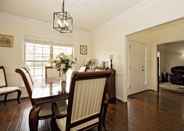 dining space with a chandelier, ornamental molding, and dark wood-type flooring