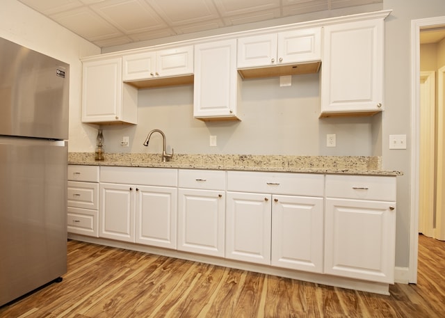 kitchen featuring stainless steel fridge, light hardwood / wood-style floors, sink, and white cabinetry