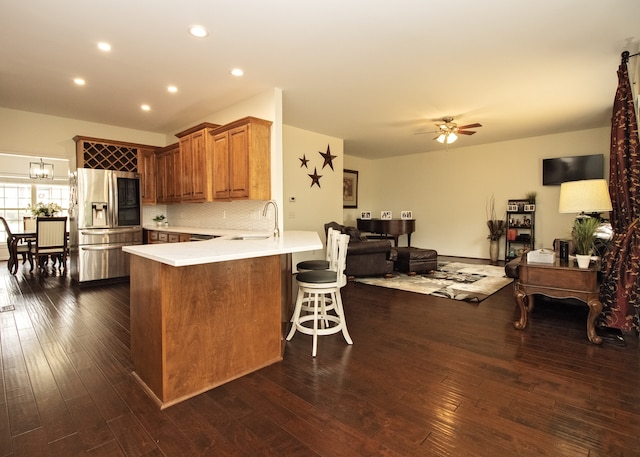 kitchen featuring stainless steel fridge with ice dispenser, dark hardwood / wood-style floors, kitchen peninsula, and a breakfast bar area