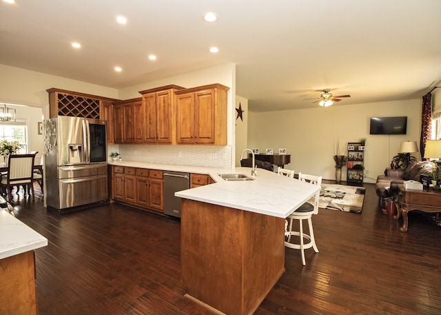 kitchen with ceiling fan with notable chandelier, sink, stainless steel fridge, dark hardwood / wood-style flooring, and kitchen peninsula