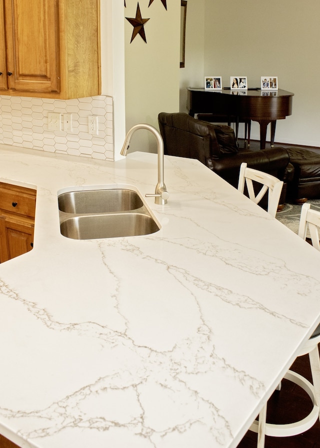 kitchen featuring kitchen peninsula, backsplash, a breakfast bar area, and sink