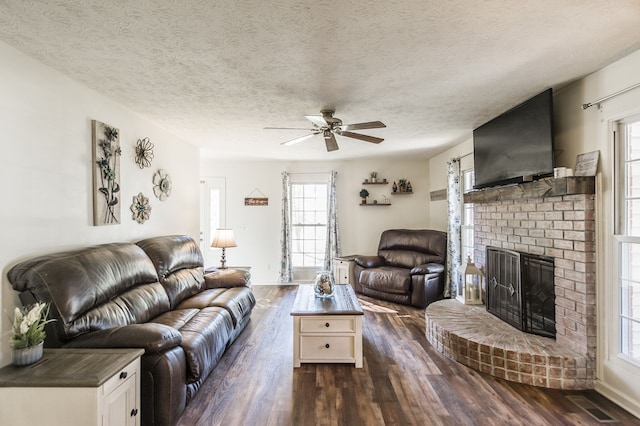 living room with a fireplace, dark hardwood / wood-style flooring, a textured ceiling, and ceiling fan