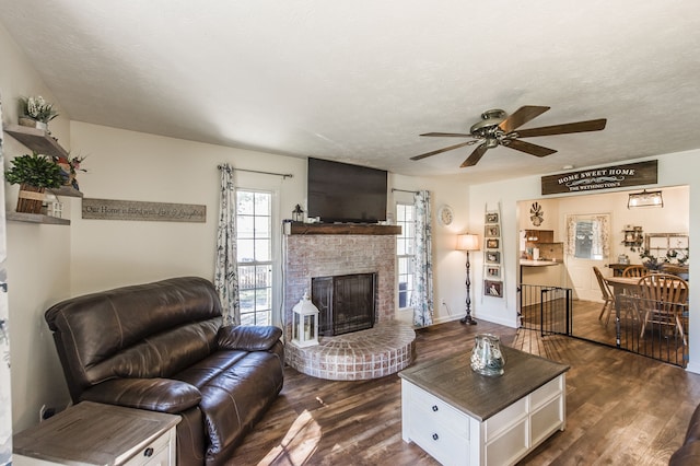 living room with a fireplace, ceiling fan, a textured ceiling, and dark hardwood / wood-style flooring