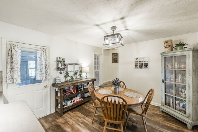 dining room with dark wood-type flooring and a textured ceiling