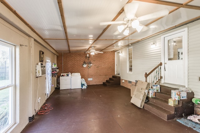 interior space featuring ceiling fan, brick wall, and independent washer and dryer