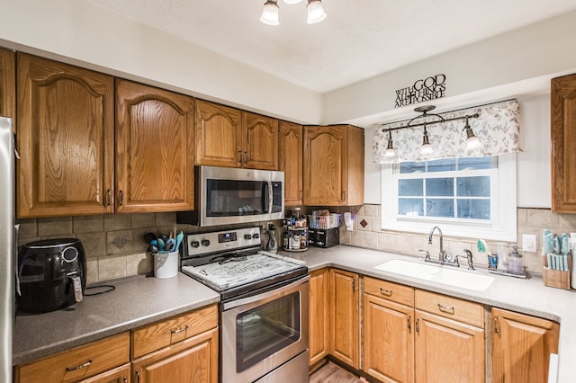 kitchen featuring a textured ceiling, decorative backsplash, sink, and stainless steel appliances