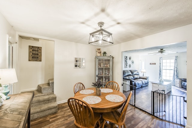 dining space with ceiling fan with notable chandelier, dark hardwood / wood-style flooring, and a textured ceiling