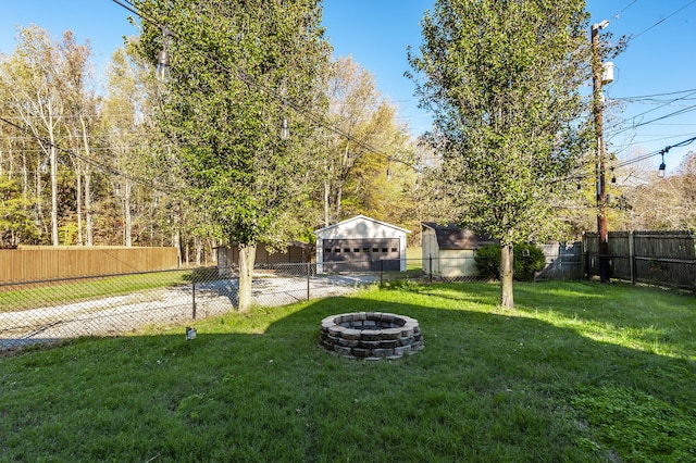 view of yard featuring an outbuilding, a garage, and a fire pit