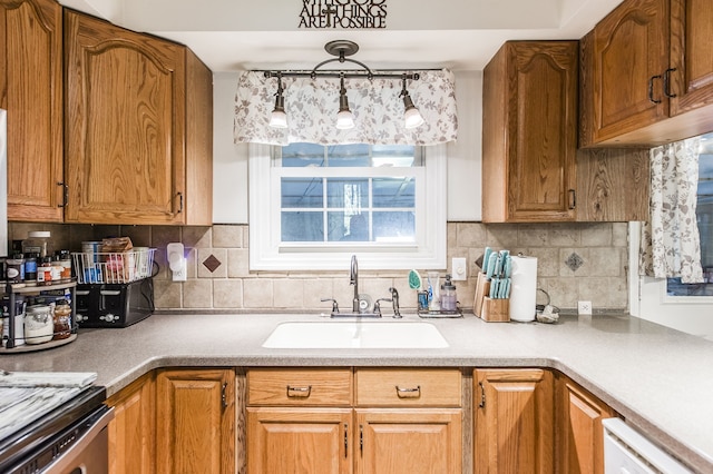 kitchen featuring backsplash, sink, decorative light fixtures, and dishwasher