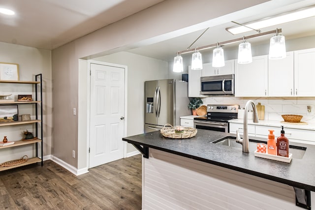 kitchen featuring sink, appliances with stainless steel finishes, hanging light fixtures, white cabinets, and dark hardwood / wood-style flooring