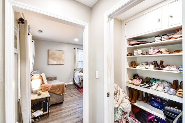 walk in closet with light hardwood / wood-style flooring