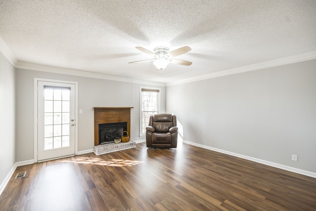 unfurnished room featuring ornamental molding, ceiling fan, a textured ceiling, dark wood-type flooring, and a brick fireplace