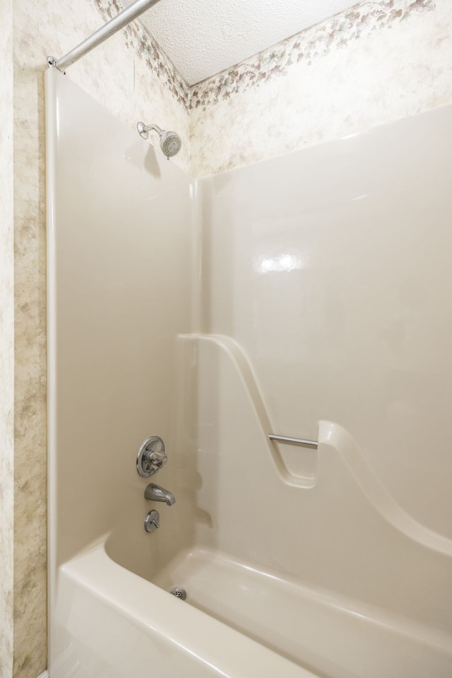 bathroom with a textured ceiling and  shower combination