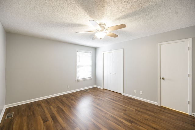 unfurnished bedroom featuring dark hardwood / wood-style flooring, a textured ceiling, and ceiling fan