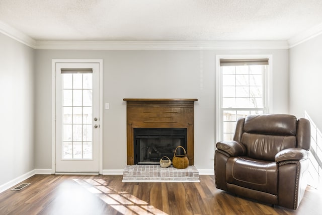 living area with wood-type flooring, ornamental molding, and a textured ceiling