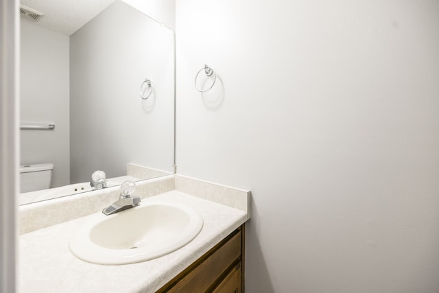 bathroom with vanity, toilet, and a textured ceiling