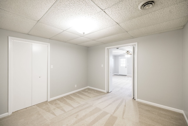 spare room with a drop ceiling, light colored carpet, and ceiling fan