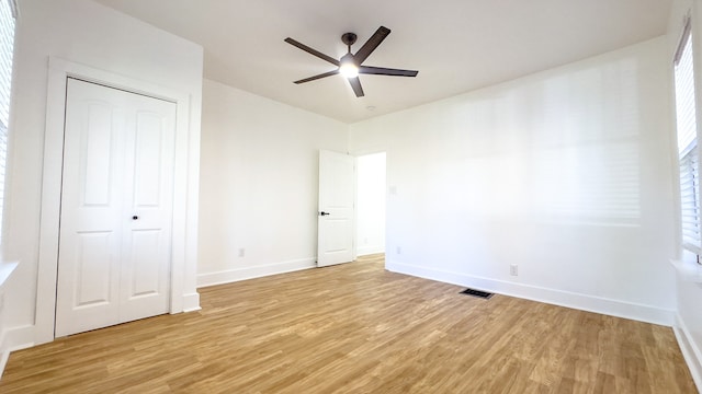 unfurnished bedroom with a closet, light wood-type flooring, and ceiling fan