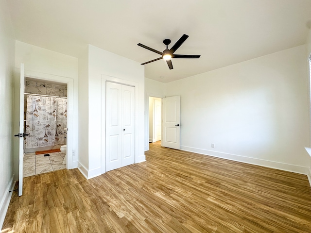 unfurnished bedroom with hardwood / wood-style floors, ensuite bathroom, ceiling fan, and a closet