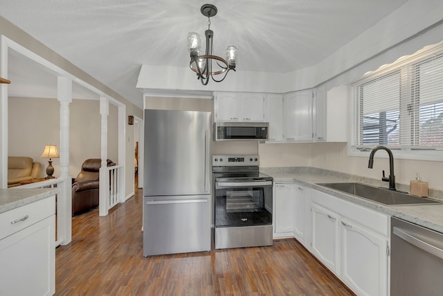 kitchen featuring stainless steel appliances, white cabinetry, dark hardwood / wood-style flooring, hanging light fixtures, and sink