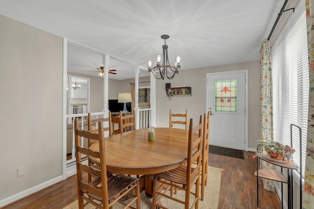 dining space featuring dark hardwood / wood-style floors, ceiling fan with notable chandelier, and decorative columns