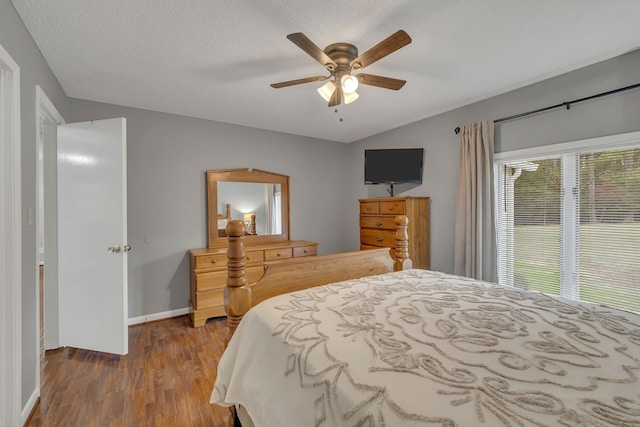 bedroom featuring a textured ceiling, hardwood / wood-style floors, lofted ceiling, and ceiling fan