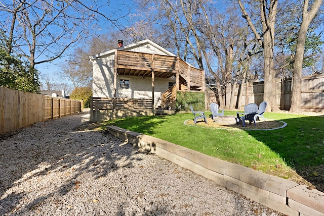 rear view of house with a deck, a lawn, and a fire pit