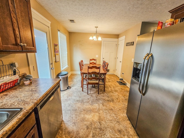 kitchen featuring stainless steel appliances, sink, a textured ceiling, an inviting chandelier, and pendant lighting