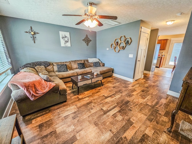 living room featuring a textured ceiling, wood-type flooring, and ceiling fan