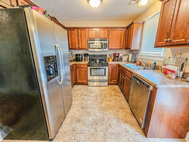 kitchen with a textured ceiling, appliances with stainless steel finishes, and sink